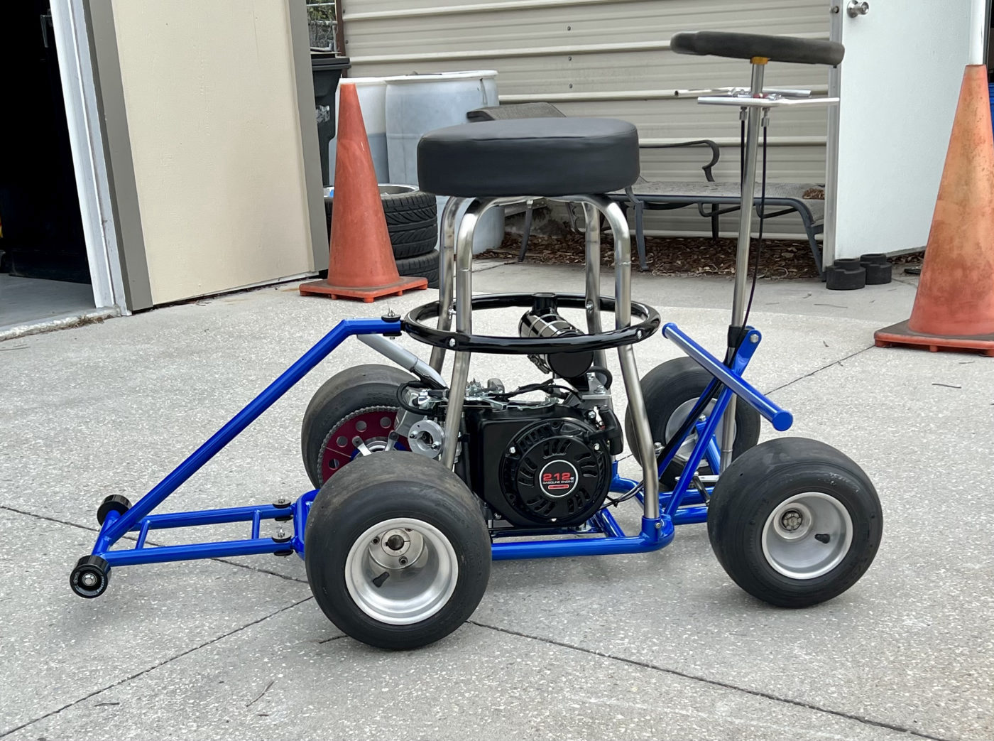 DKCC Bar-Hag — rear three-quarter view outdoors showing 212cc engine and full stance with Harley alongside