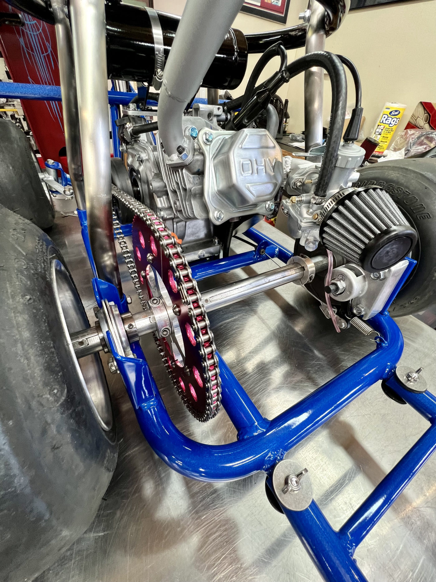 DKCC Bar-Hag — rear axle close-up showing OHV engine, red anodized sprocket and Bridgestone slick detail